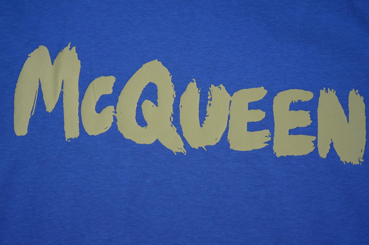 Blue crewneck T-shirt close-up with McQueen lettering in pale green