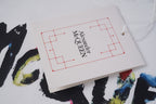 Alexander McQueen clothing tag on white paper with red logo lines and Est. lettering