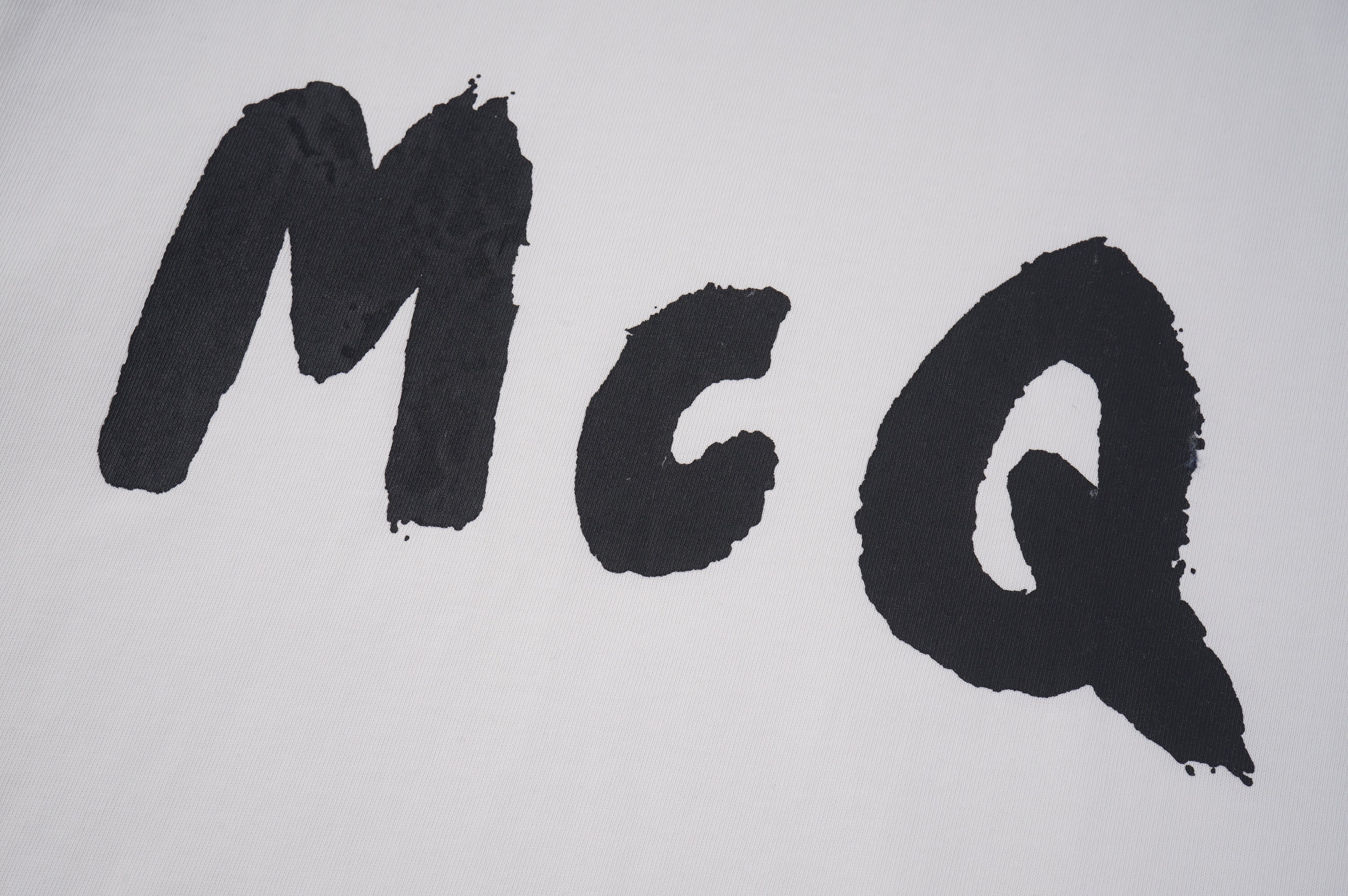 Alexander McQueen T-shirt close-up, large black McQ letters on light fabric