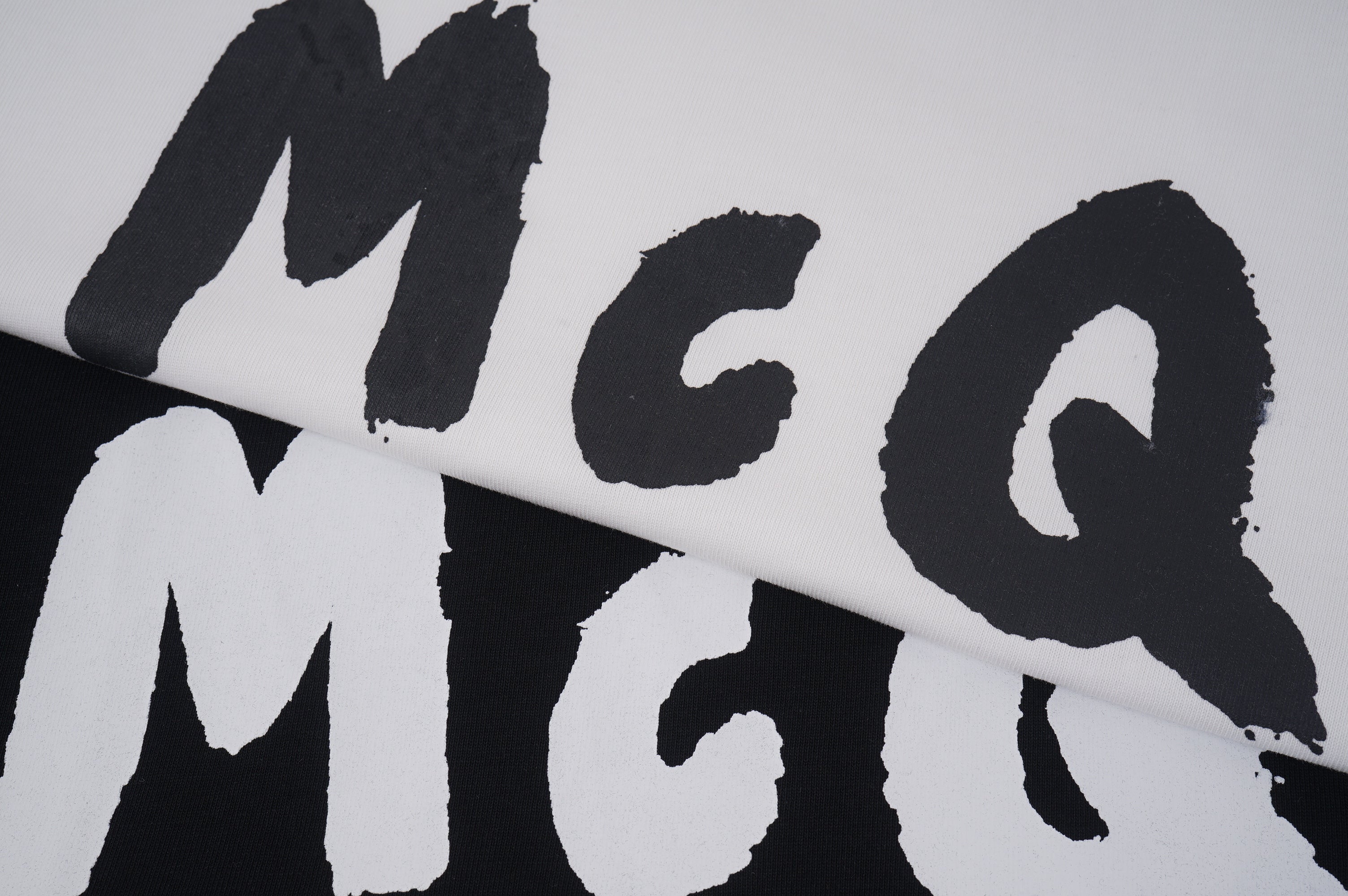Alexander McQueen T-shirt close-up, black McQ letters on light fabric