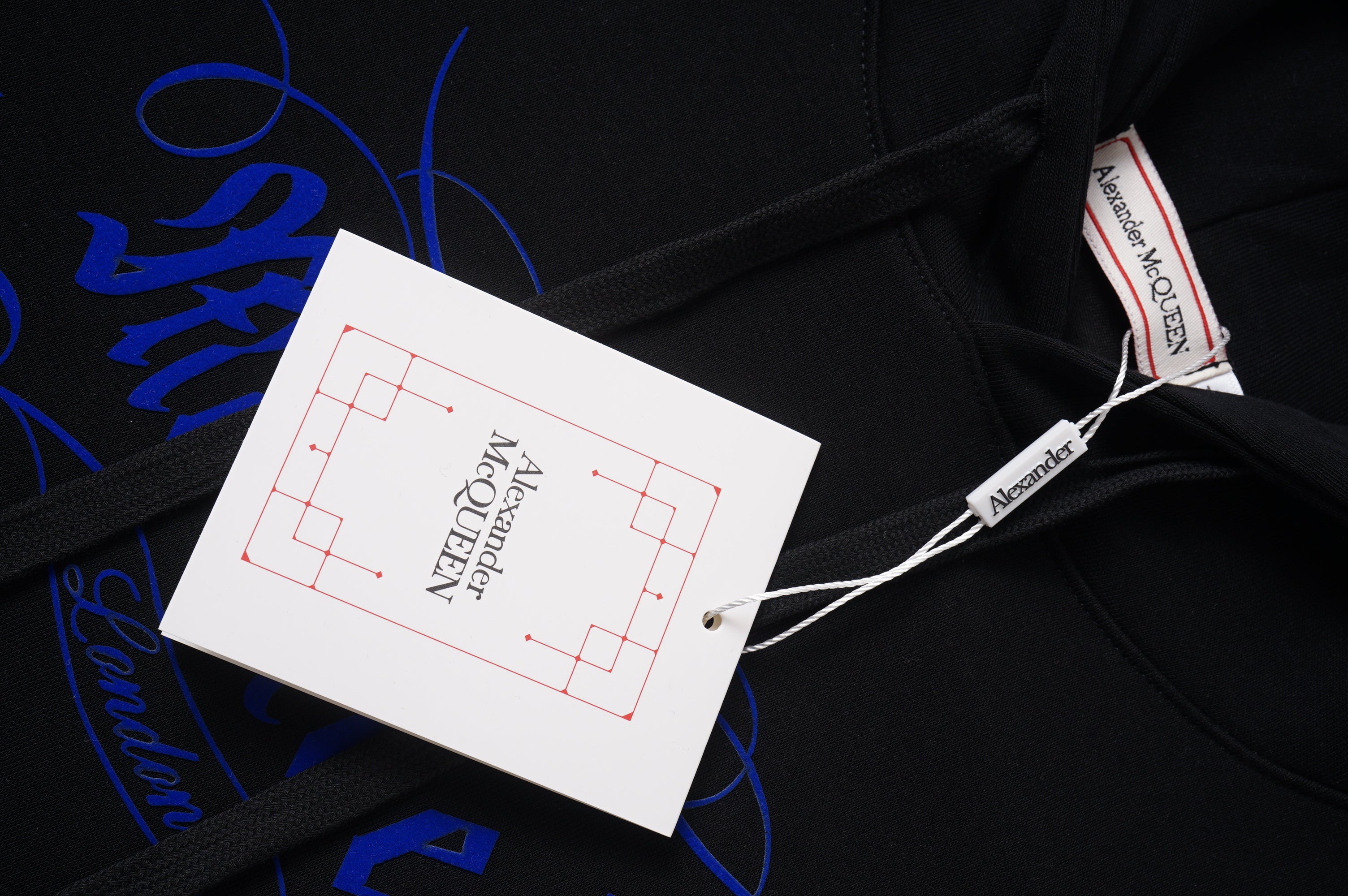 Black hoodie with hood drawstrings and brand tag at the neckline