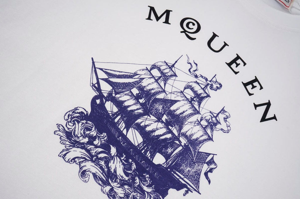 White T-shirt close-up with blue pirate ship graphic and curved McQueen letters