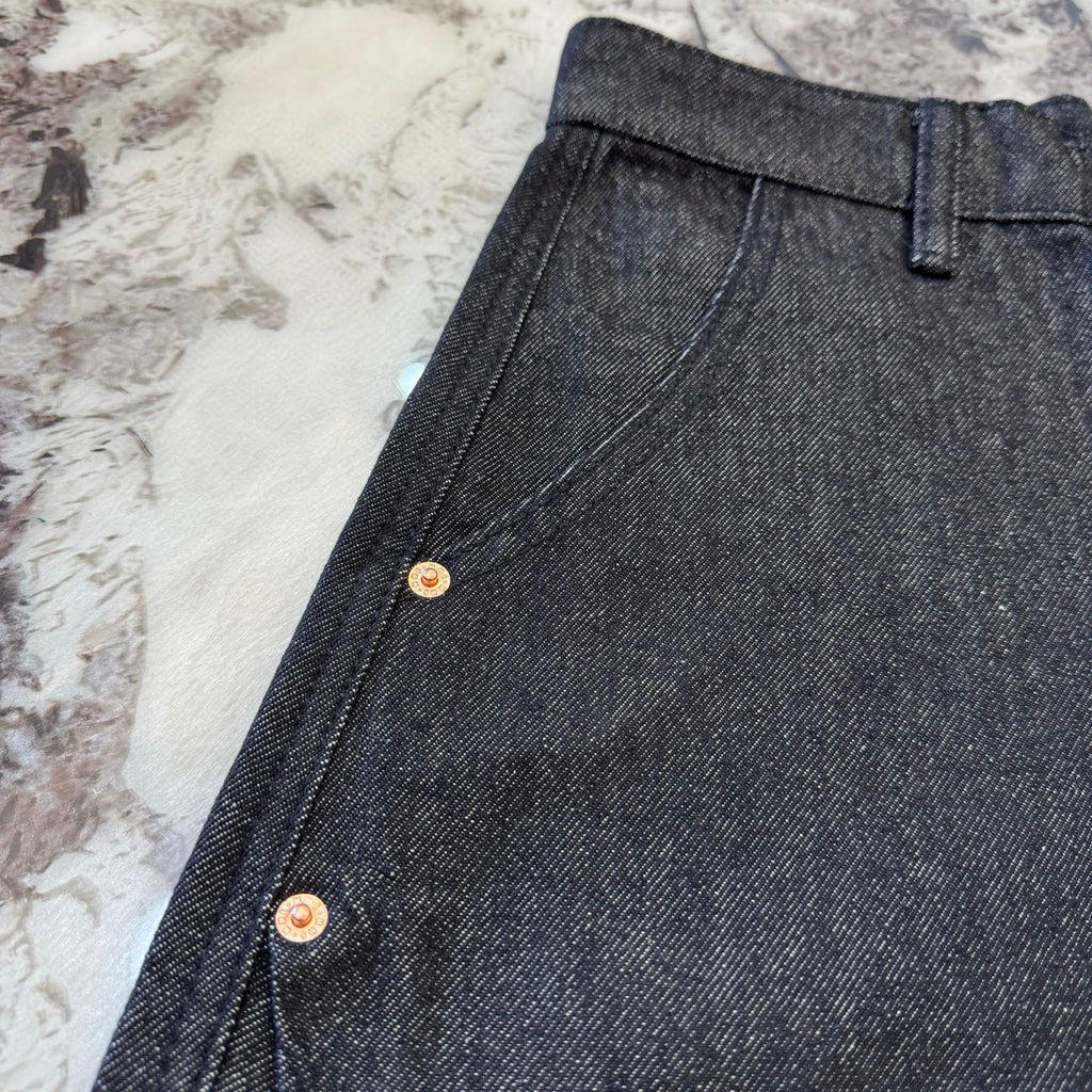 Dark denim shorts side seam close-up with gold-tone button snaps
