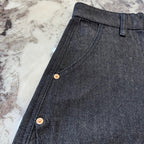Dark denim shorts side seam close-up with gold-tone button snaps