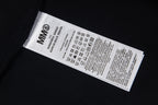 Black T-shirt with interior neck label and care symbols, sleeve edge visible.