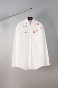 White button-up shirt with red lip print, front view on hanger