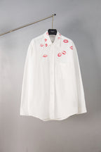 White button-up shirt with red lip print, front view on hanger