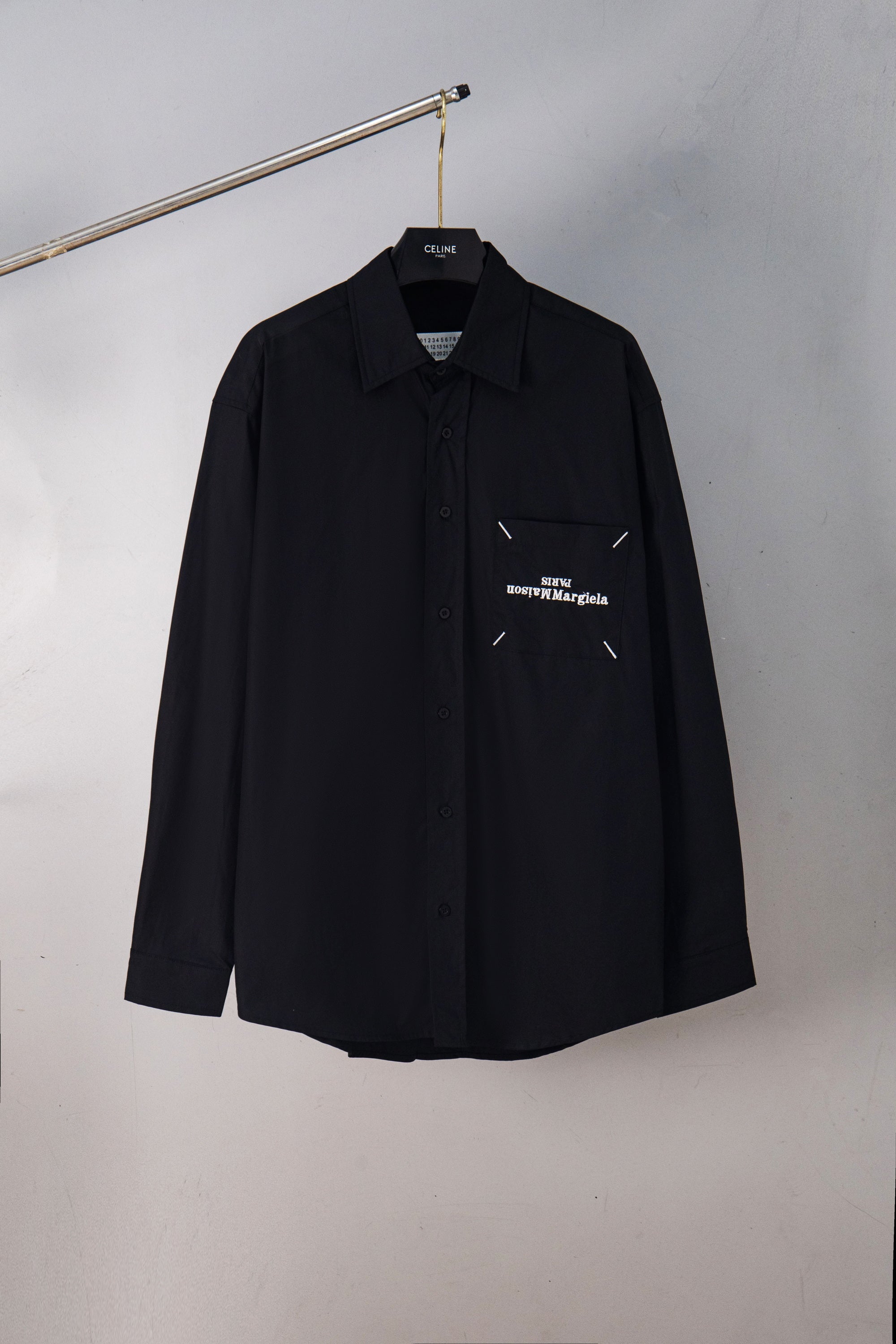 Black button-up shirt with pointed collar and chest logo detail