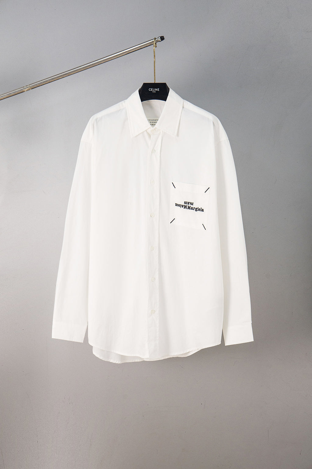 White button-up shirt with pointed collar and chest logo detail