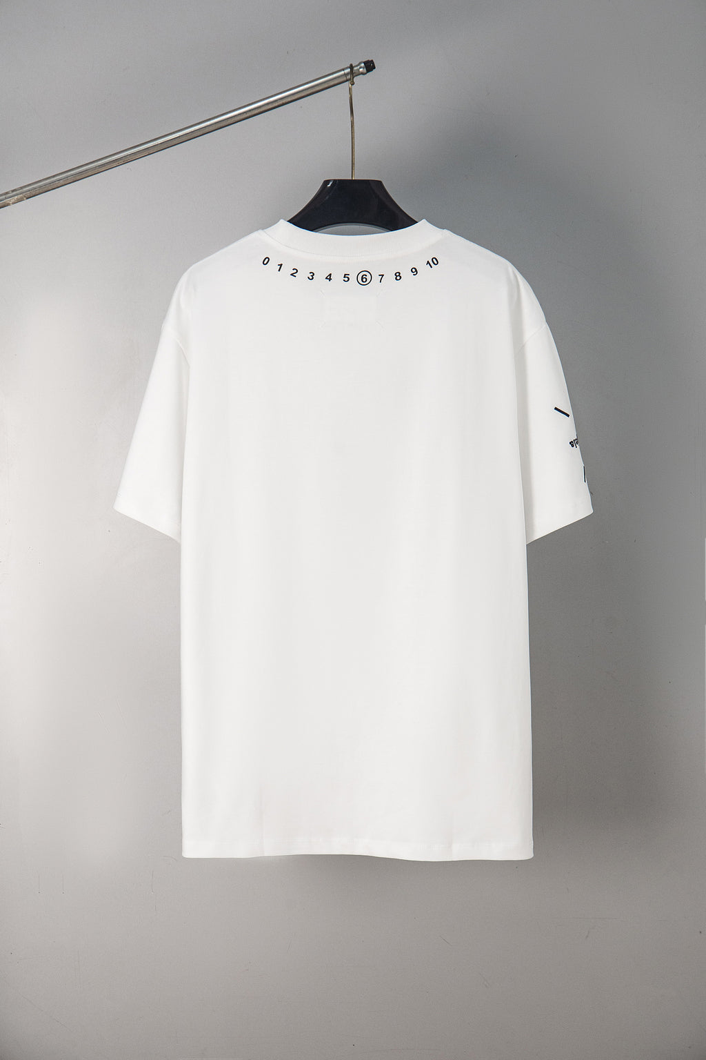 White crewneck T-shirt with number graphic on back yoke, short sleeves.