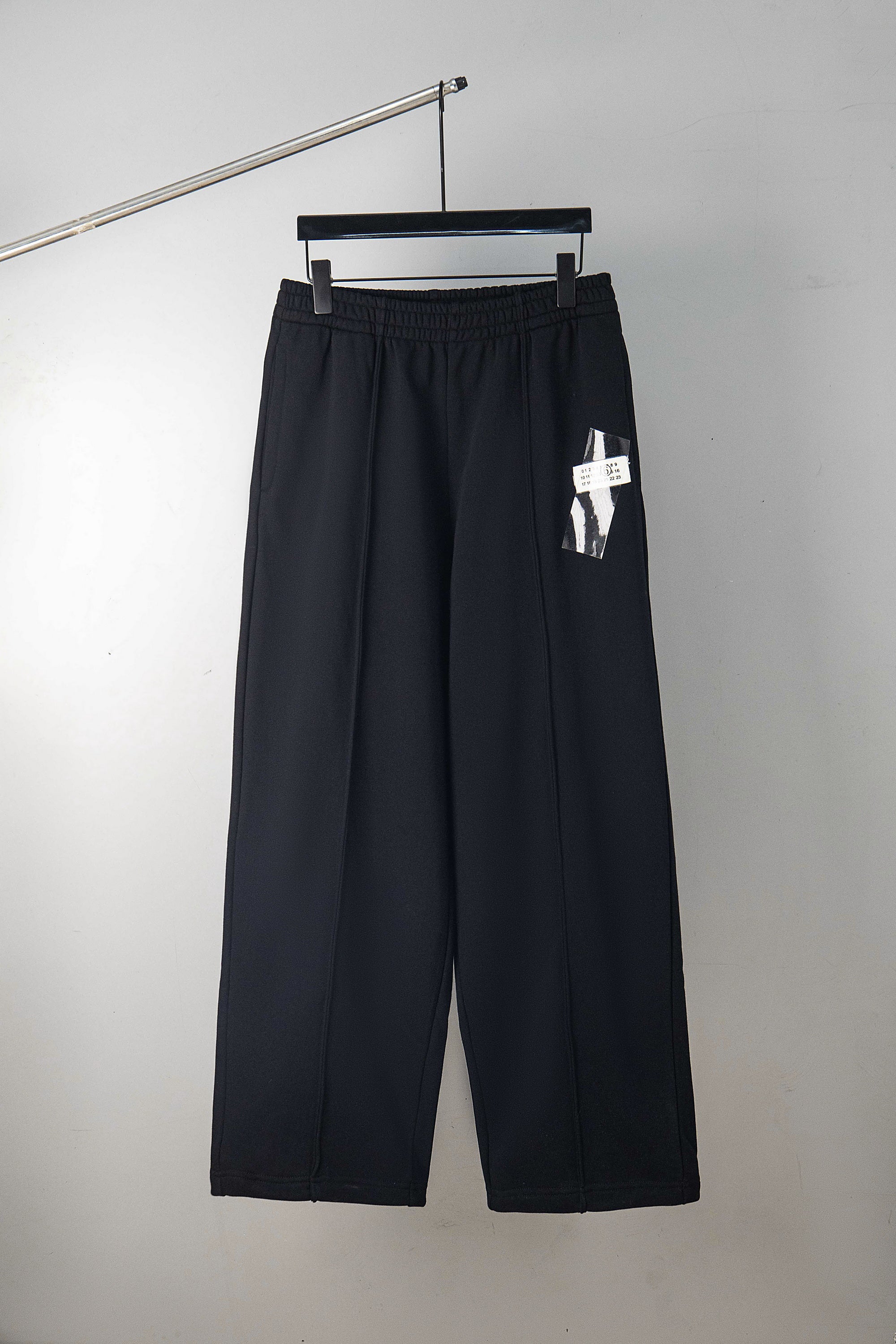 Dark wide-leg trousers with elastic waistband and hanging tag