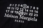 Dark shirt close-up with number graphic and Maison Margiela Paris text