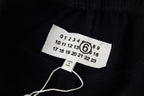 Black fabric clothing label with size numbers and circular 6 logo