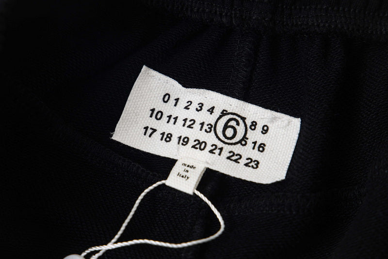 Black fabric clothing label with size numbers and circular 6 logo
