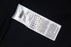 Clothing label inside black T-shirt with care and size information