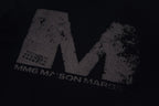 Close-up of black graphic T-shirt with distressed M logo print