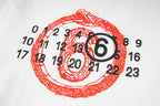 Close-up: white long-sleeve T-shirt chest print, red circular number emblem
