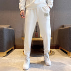 White jogger pants with small logo label near thigh and elastic cuffs