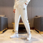 White jogger pants with small logo label on thigh and cuffed hems