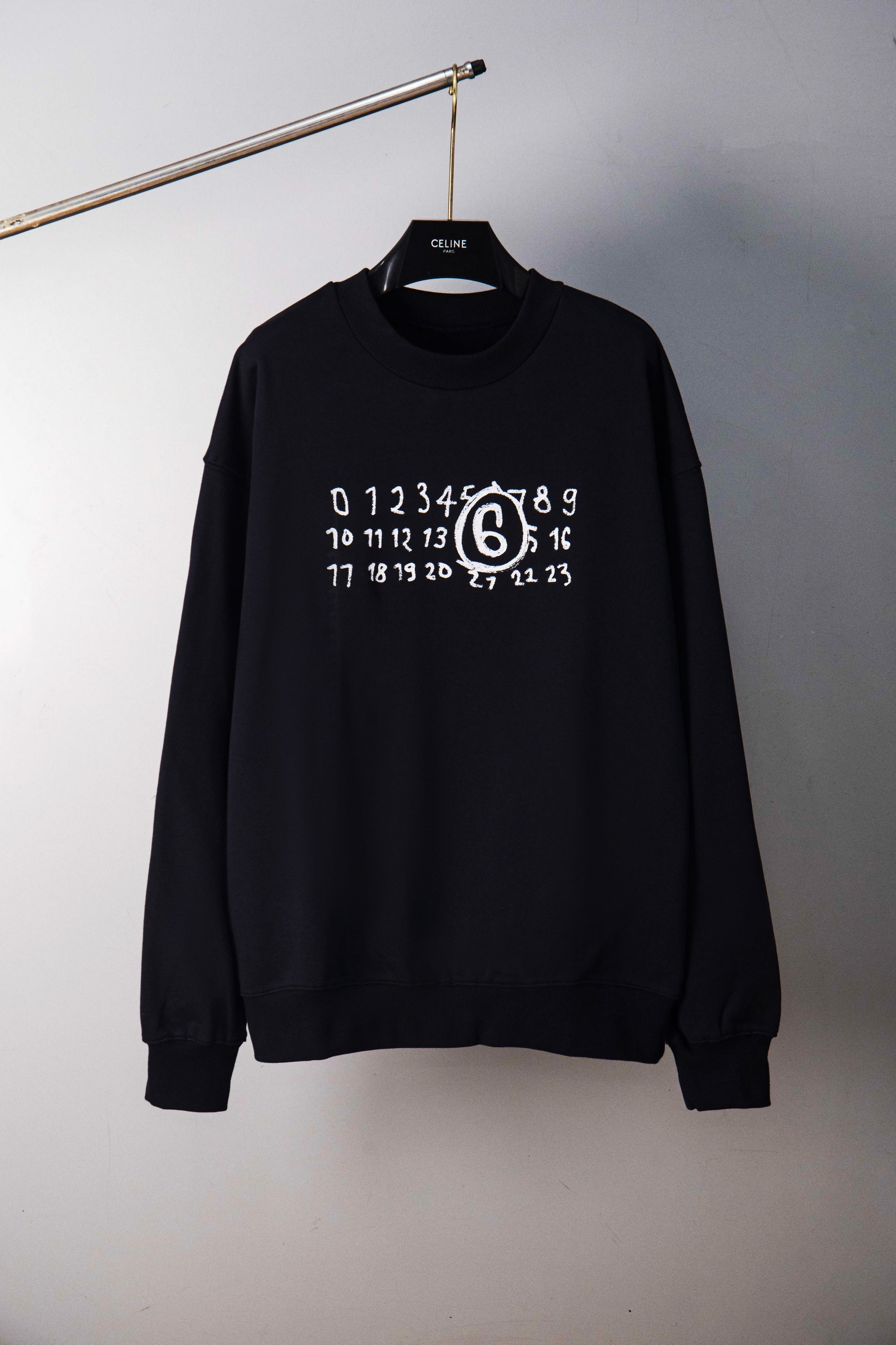 Black crewneck sweatshirt with numbered ring graphic, hanging view