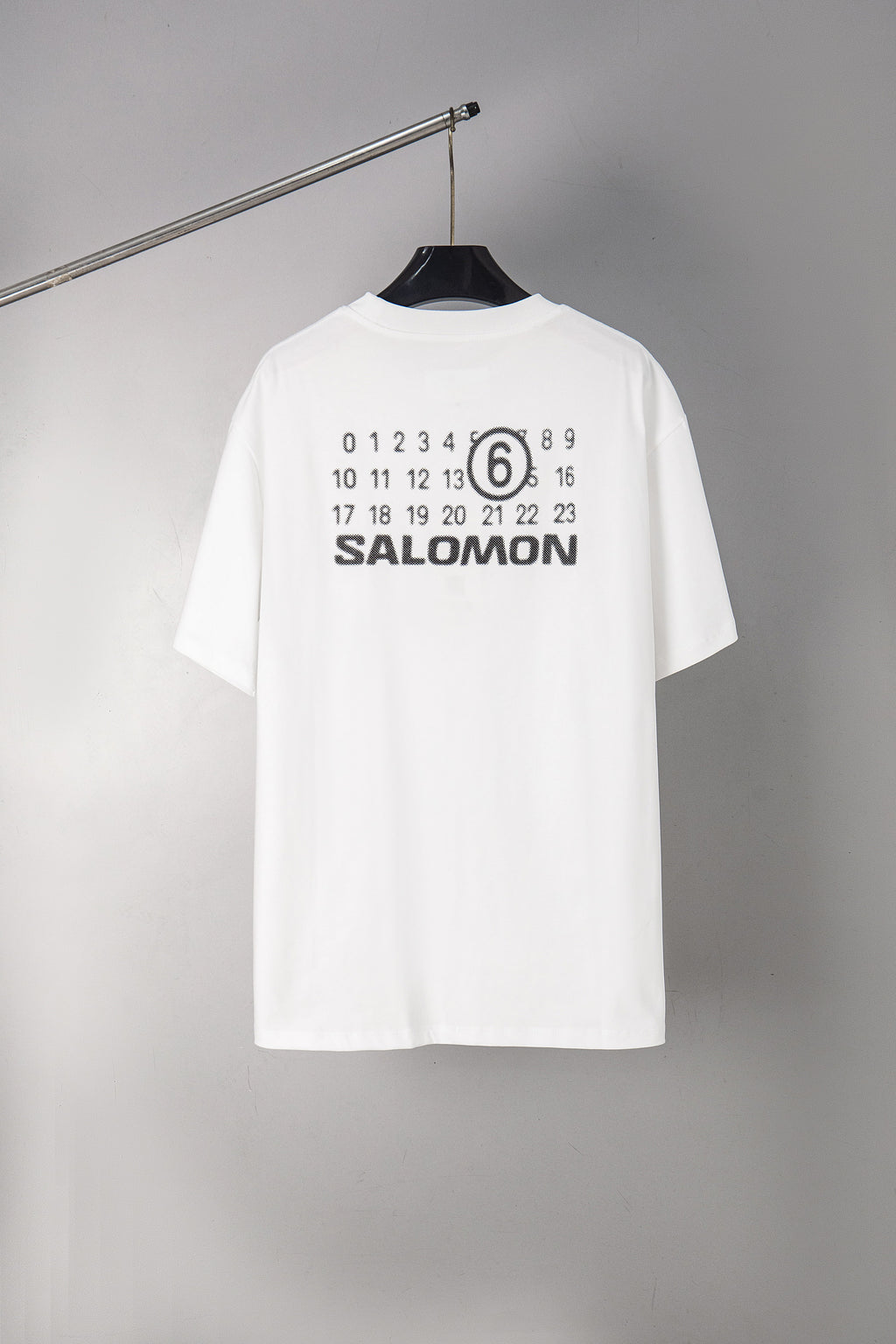 Back of white T-shirt with SALOMON graphic and number 6 print