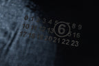 Close-up of black fabric with numeric logo print in light gray