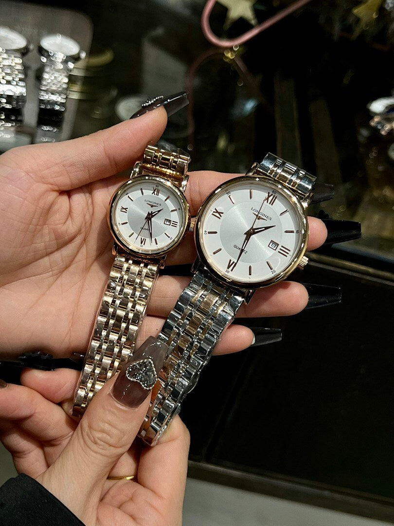 Two wristwatches with silver metal bracelets, one white dial and one light dial, held.