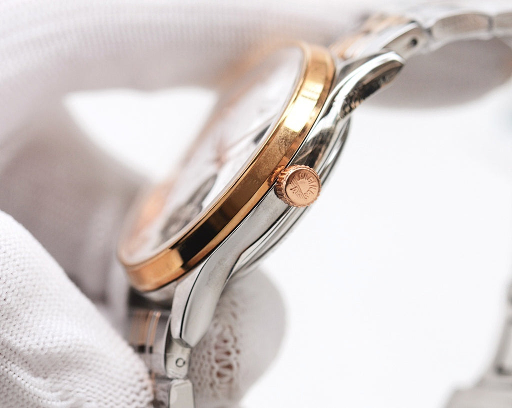 Stainless steel watch case with rose gold crown detail and metal strap