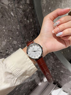 Longines watch with white dial and brown leather strap on hand, round case