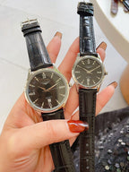 Pair of watches with dark dials, black leather straps, silver cases
