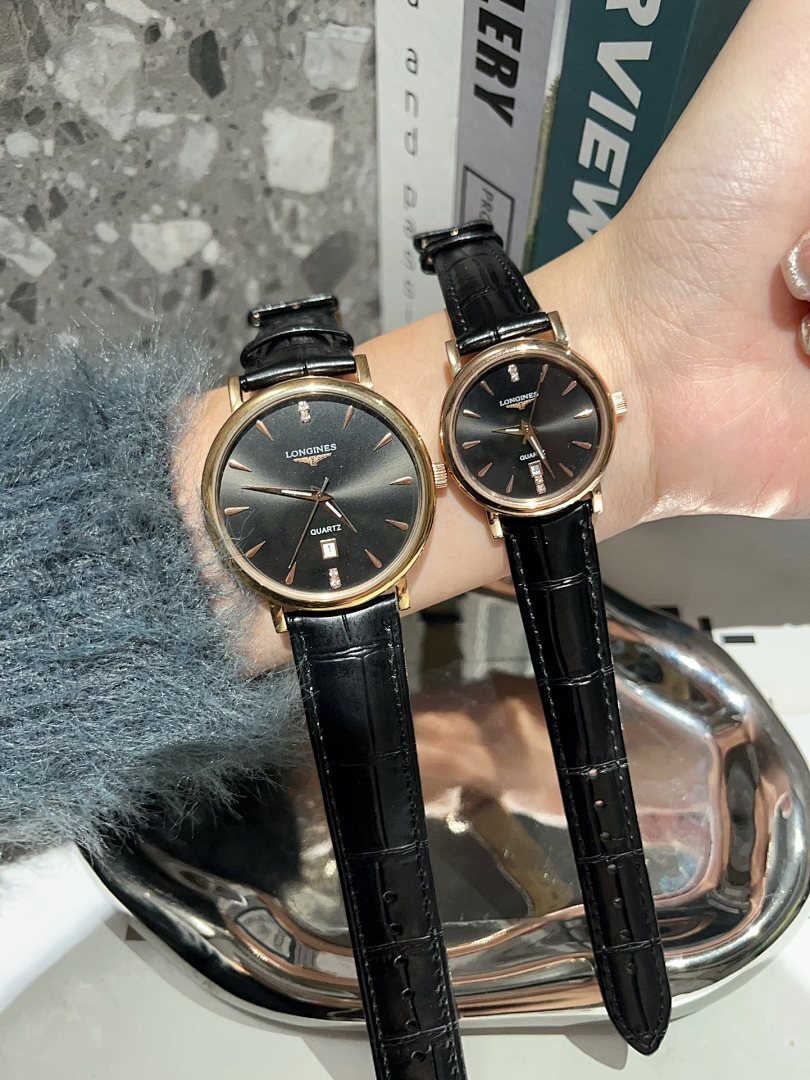 Analog wristwatches with dark dials and black leather straps held up