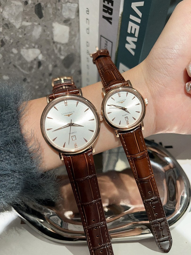 Analog wristwatches with white dials and brown leather straps on hand