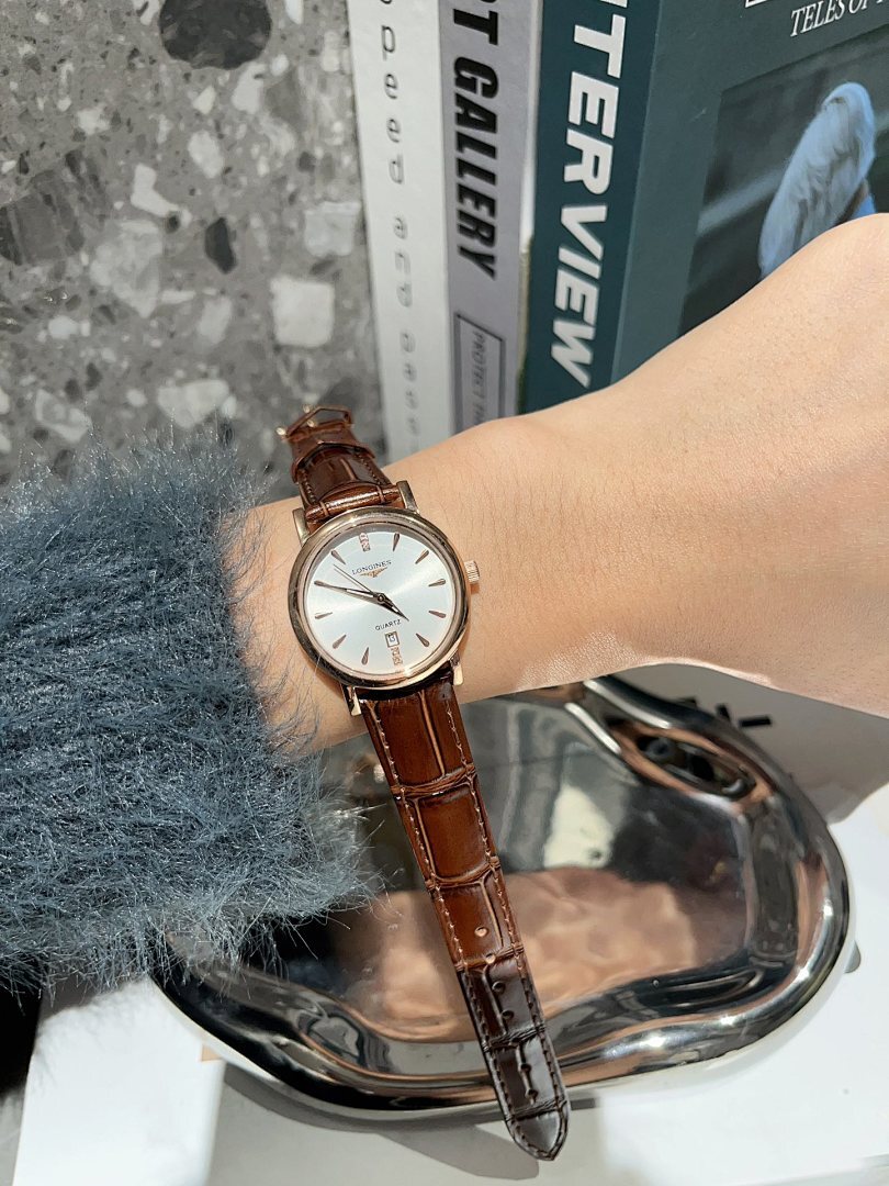 Analog wristwatch with white dial and brown leather strap on wrist