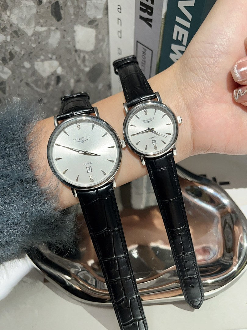 Analog wristwatches with white dials and black leather straps on hand