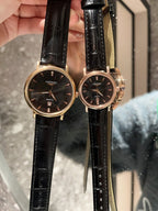 Analog wristwatches with dark dials and black leather straps, gold cases