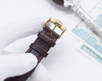 Longines leather watch strap close-up with gold-tone buckle, brown leather