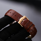 Brown leather watch strap with gold-tone buckle, stitched edges