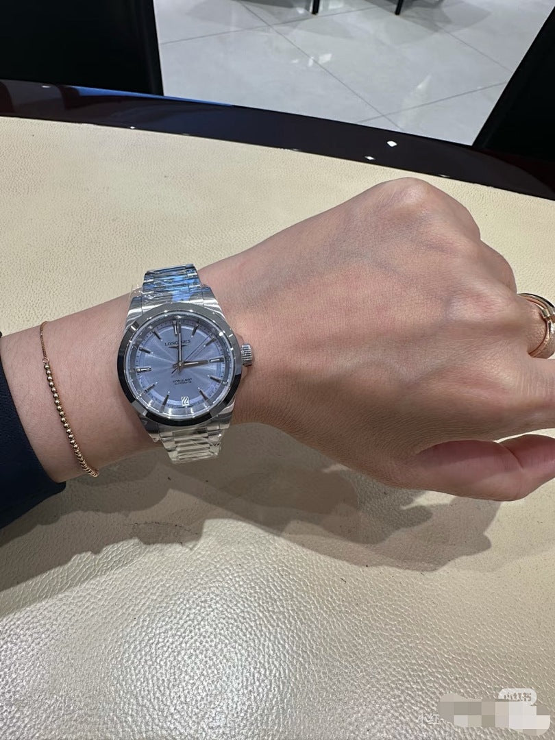 Stainless steel wristwatch with blue dial and metal bracelet on forearm
