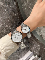 Longines watch pair on wrists with silver metal bracelets and white dials