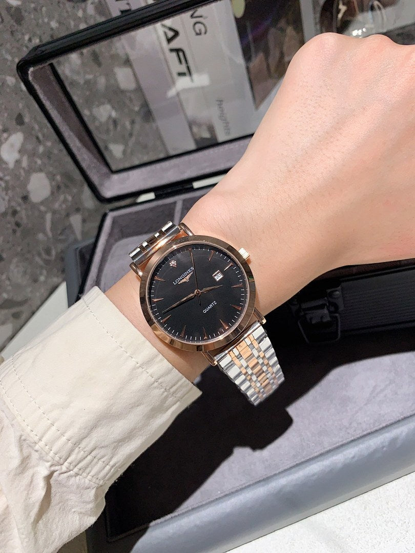Longines watch on wrist with black dial, gold-tone bezel, and silver metal bracelet