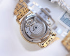 Gold-tone metal watch case with exposed mechanical movement view