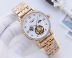 Gold-tone metal watch with white dial, jeweled bezel, and openwork movement