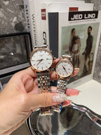 Longines watch with white dial and silver metal bracelet, held next to a smaller watch