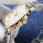 Two-tone watch crown and gold-toned knob on the side of a stainless steel case