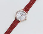 Wristwatch with red leather strap, white dial and crystal-studded bezel