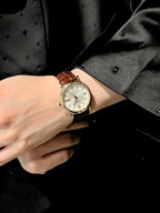 Luxury wrist watch with gold-tone case and white dial on a light strap