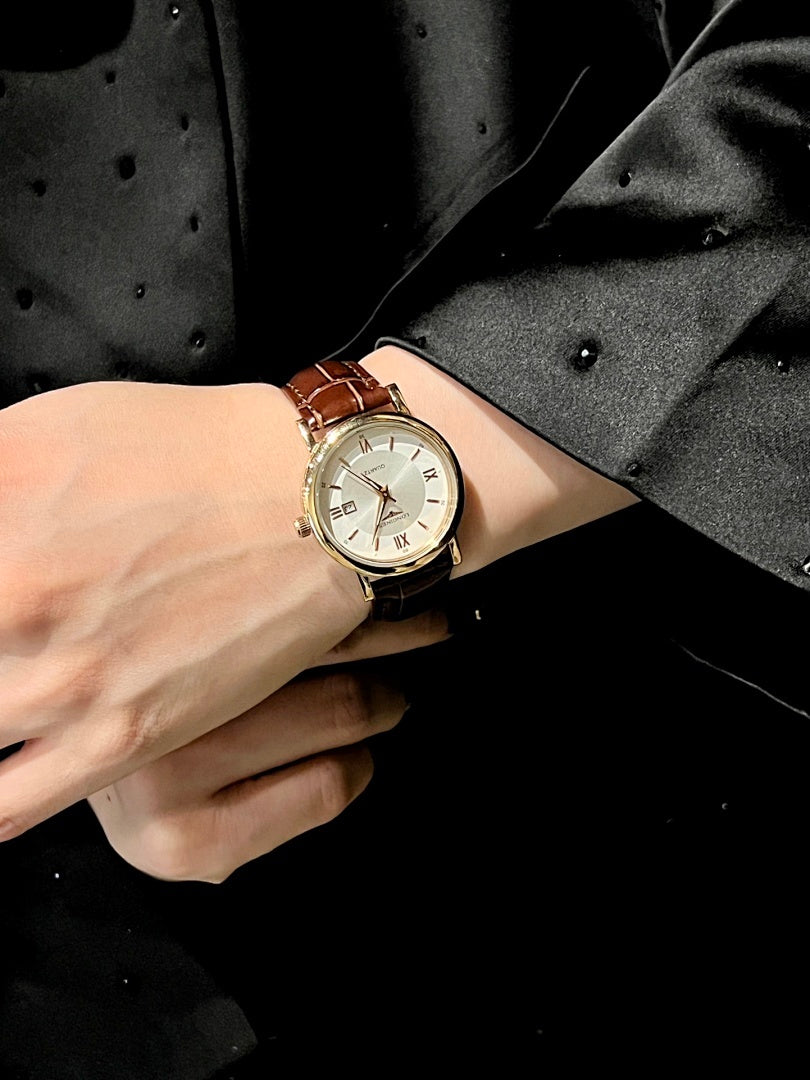 Luxury wrist watch with gold-tone case and white dial on a light strap