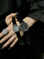 Pair of luxury wrist watches with black leather straps and silver-tone dials