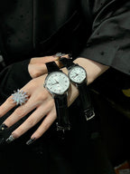 Pair of luxury wrist watches with black leather straps and light dials