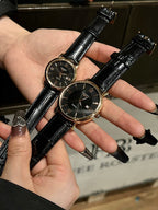 Pair of luxury wrist watches with black leather straps and dark dials